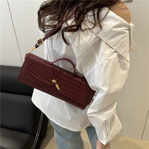 Deep red crocodile embossed baguette bag with gold lock and adjustable strap on model