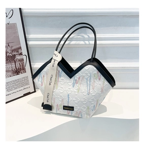 Détail du sac cabas matelassé blanc avec broderies ondulées et finitions noires chic