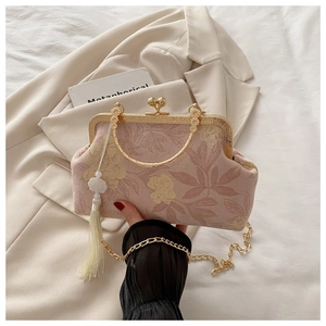 Close-up of pink floral vintage handbag with golden handle, chain strap and white tassel