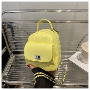 Close-up of bright yellow quilted mini backpack with silver twist lock and chain strap