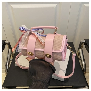 Pink cylinder handbag featuring woven texture, gold metal buckles and lace ribbon handle detail