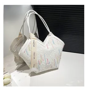 Détail d'un sac cabas blanc en forme de V avec surpiqûres colorées et texture matelassée