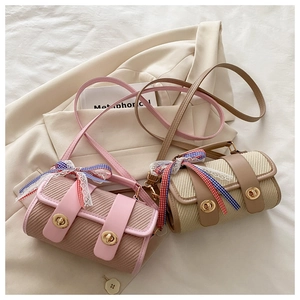 Detail showing two woven cylinder crossbody bags with metallic locks and ribbon accents