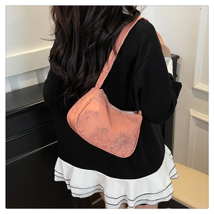 Detail of the pink underarm bag with bamboo leaf patterns shown on a shoulder