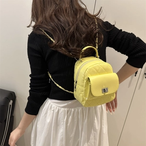 Bright yellow quilted mini backpack with silver twist lock and woven chain straps