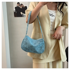 Detail of light blue hobo bag with bamboo leaf print on a model in yellow suit