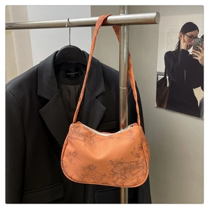 Detail of orange baguette bag with bamboo print and smooth nylon texture on a hanger