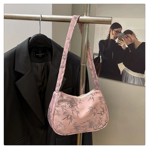 Detail of pink satin underarm bag with dark bamboo leaf print in a chic office setting