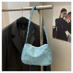 Detail of light blue bamboo leaf print handbag with retro handle and zipper closure