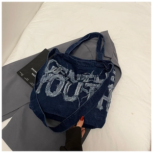 Close-up of denim tote bag featuring frayed YOUTH lettering and street style design