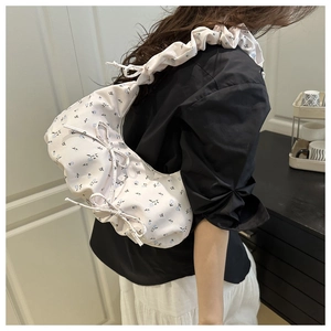 Detail of floral shoulder bag with ruffled straps and side bow on a female model