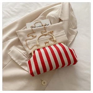 Detail of red and white striped canvas clutch featuring gold metal clasp and chain strap