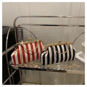 Retro striped doctor bag with gold metal frame and chain strap on modern shelf