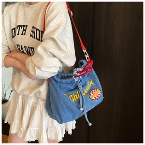 Detailansicht der Denim-Beuteltasche mit gelber Stickerei, rotem Gurt und Kordelzug