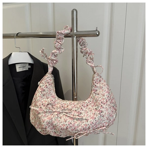 Detail of floral hobo bag with ruffle handle, ribbon bows, and crescent moon shape