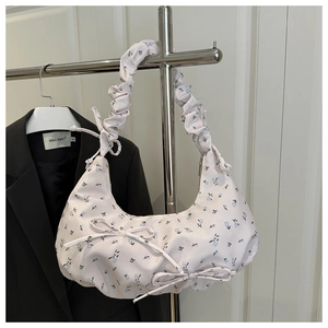 Close-up of floral shoulder bag with ruched handle and bow detail on pastel fabric