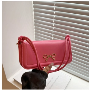 Detailed macro view of a pink leather baguette bag featuring a golden bow metal buckle