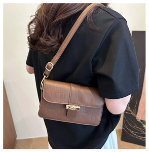 Detail of brown crocodile pattern shoulder bag with a vintage gold bamboo lock
