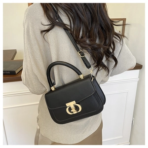 Détail du sac en cuir noir avec fermoir doré et bandoulière amovible réglable