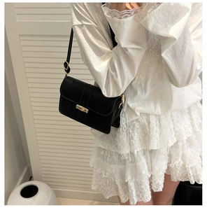 Detail of minimalist black crossbody bag with gold bamboo style clasp for women