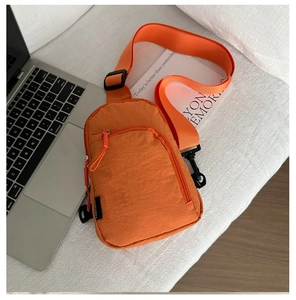 Détail d'un sac de poitrine en nylon orange vif avec sangle réglable et poches zippées