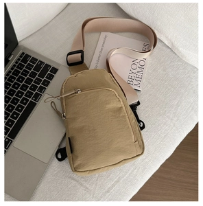 Sac bandoulière en nylon kaki avec sangle réglable posé sur un canapé blanc chic