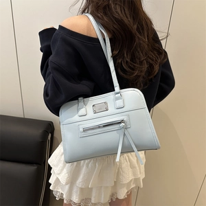 Hellblaue Schultertasche aus Kunstleder mit Quasten und Metallplatte in Lifestyle-Ansicht