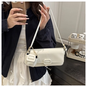 Detailed view of white litchi pattern baguette bag with mini purse charm and gold hardware