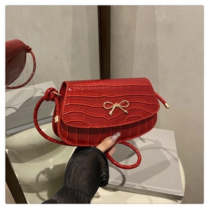 Detail of red crocodile texture square bag with elegant gold bow metal clasp and PU leather