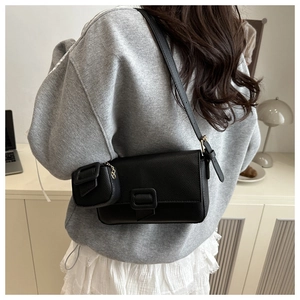 Detailed view of black baguette bag with litchi texture and matching mini pouch hanging