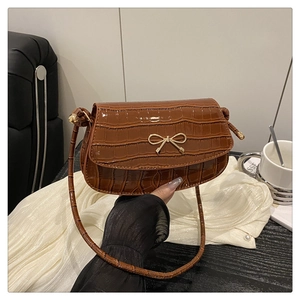 Close-up of brown crocodile texture leather bag with elegant gold metal bow clasp