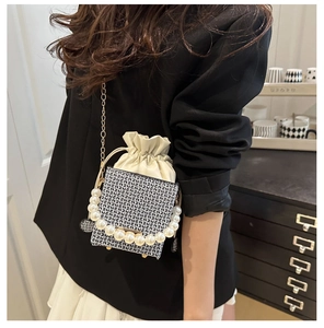 Detail einer Vintage Box-Tasche mit Perlengriff und Goldkette auf einem Vintage-Schrank
