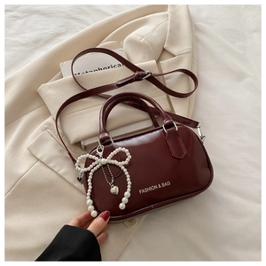 Detail of wine red patent leather mini bag with pearl bow charm and heart pendant