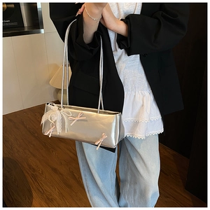 Silver underarm bag with pink bows and lace pendant shown as a stylish shoulder bag style