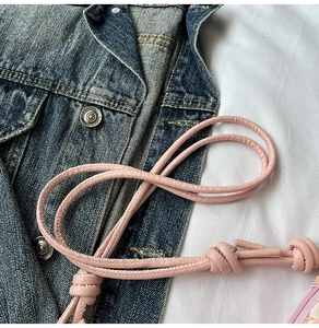 Detail of pink leather strap with handcrafted knot design on a casual denim backdrop