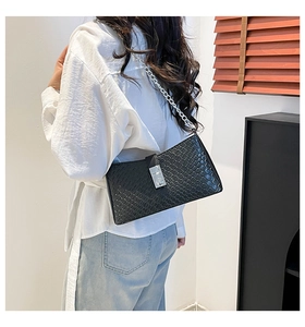 Détail du sac tressé noir avec une chaîne en métal argenté et fermoir magnétique