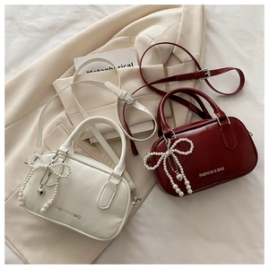 Detail of elegant pearl bow and heart charm on retro leather top handle bags