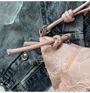 Detail of pink lace shoulder bag with 3D butterfly appliqué and knotted strap
