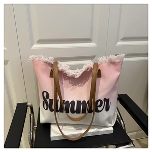Close-up of pink tassel trim on a gradient canvas beach tote with Summer print