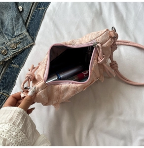Detail view showing interior space of pink embroidered hobo bag with cosmetics inside