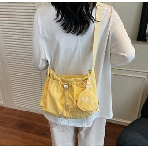 Minimalist yellow drawstring shoulder bag with a round coin purse in a casual nylon style