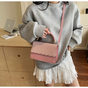 Detailed view of pink PU leather bag featuring woven texture and scalloped edges
