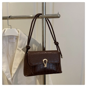 Detailed view of brown crocodile texture shoulder bag with golden U-shaped buckle