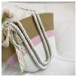 Detail of woven beach tote showing color-block stripes and decorative lace bow