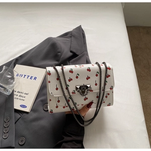 Détail du sac bandoulière en PU blanc avec imprimé cerises et fermoir en métal noir