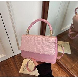 Detail of light pink crossbody bag featuring woven texture flap and wavy edges