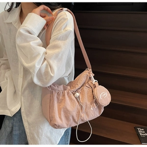 Pink nylon crossbody bag with drawstring detail and round coin purse shown on a model