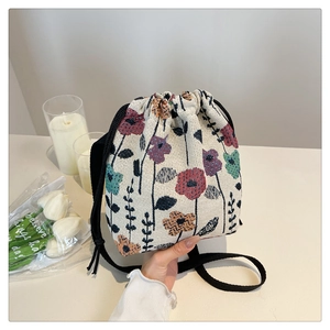 Close-up of drawstring bucket bag with vintage floral tapestry and black woven strap