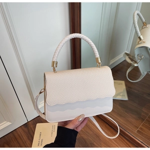 Detail of off-white crossbody bag featuring woven texture flap and golden metal buckle