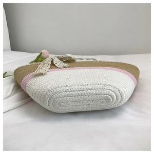Detail of color-block woven tote bag with lace bow on a soft white fabric surface